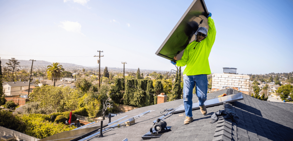 Man installing solar panels on roof of home.