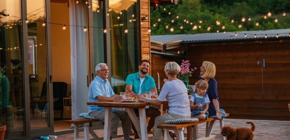 Multigenerational family enjoying dinner outside on a patio along with the family dog.