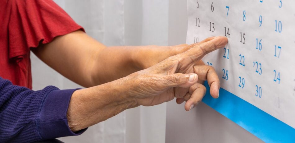 Close up of two women's hands pointing to a calendar.