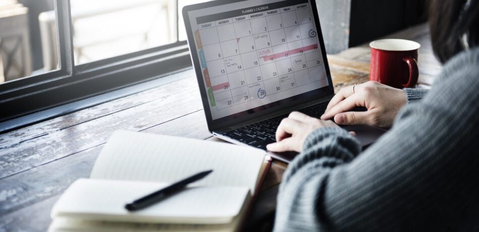 Woman working on her laptop with an open journal next to her.