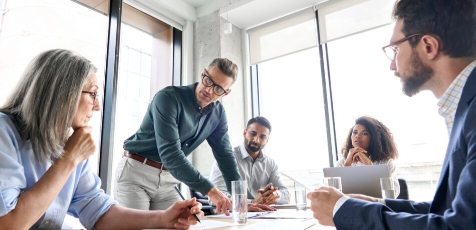 Group of employees around a conference table discussing a work project.