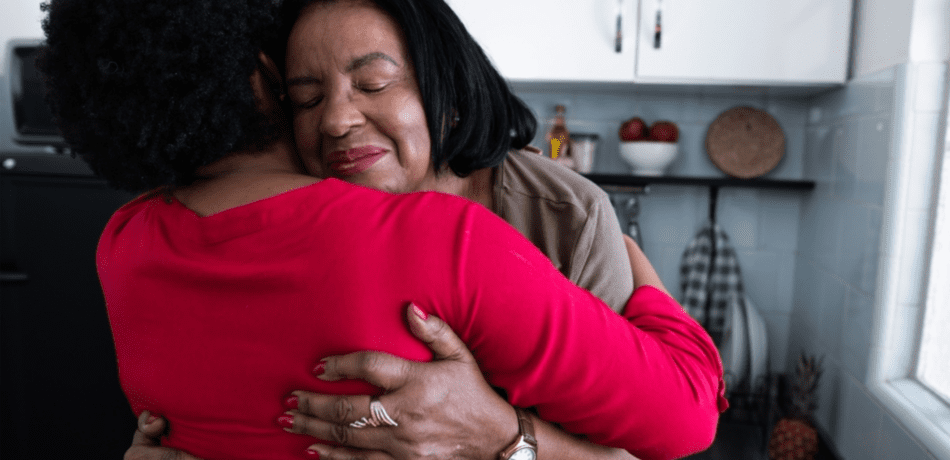 Woman hugging another woman in a kitchen.