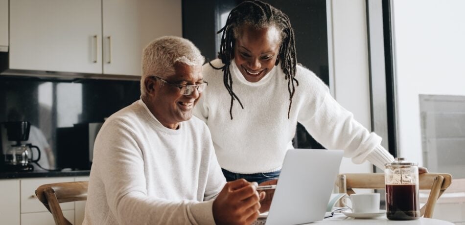 An older couple looks at a laptop.