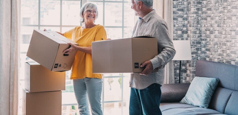 An older couple moves boxes into their new home.