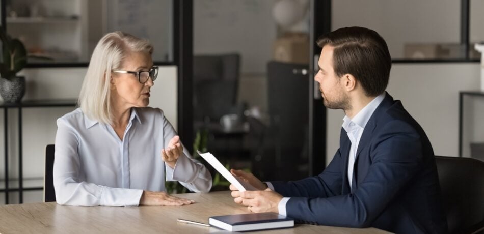 Two people speak in an office conference room.