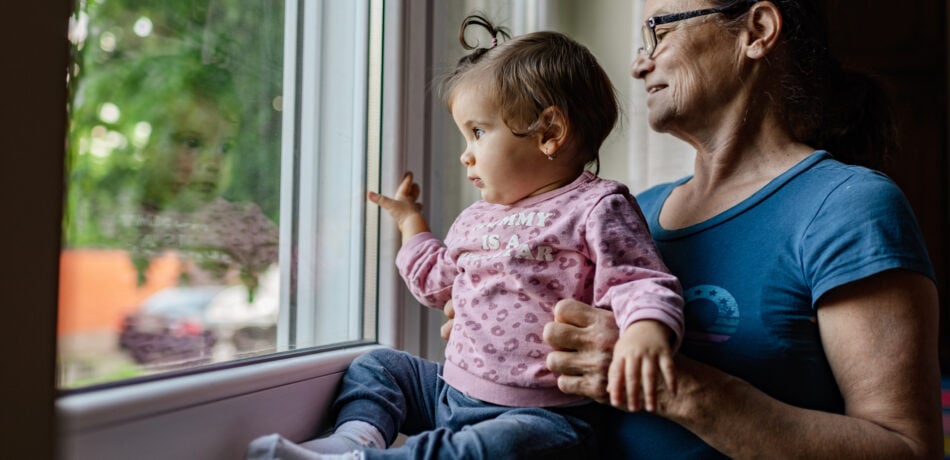 Grandmother and baby girl looking through the window.