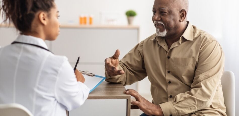 An older man talks with a doctor in a medical office.