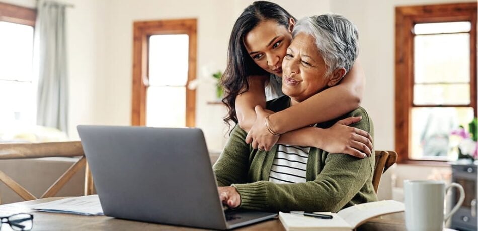 A mother and adult daughter review Medicare coverage options on a laptop at home.