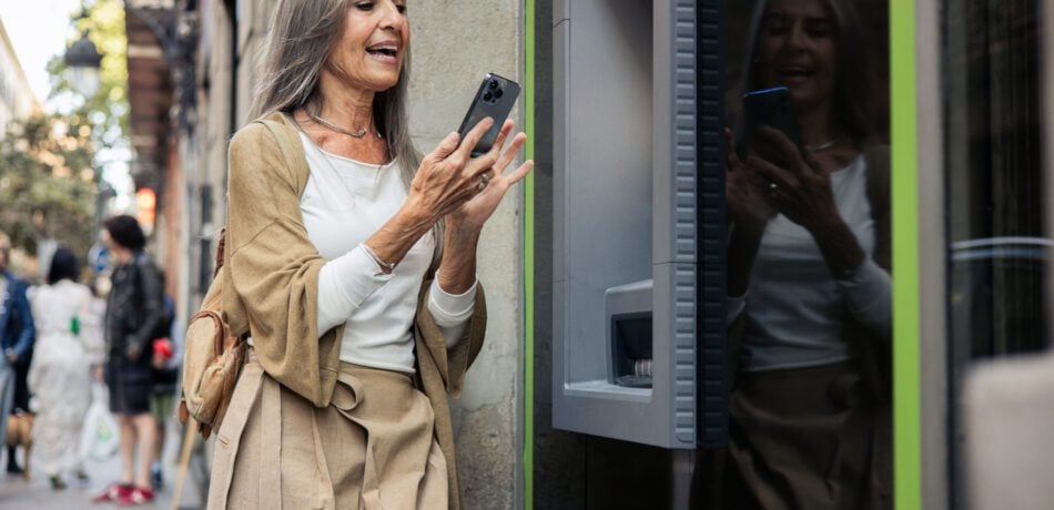 Mature woman using an ATM machine on a street.