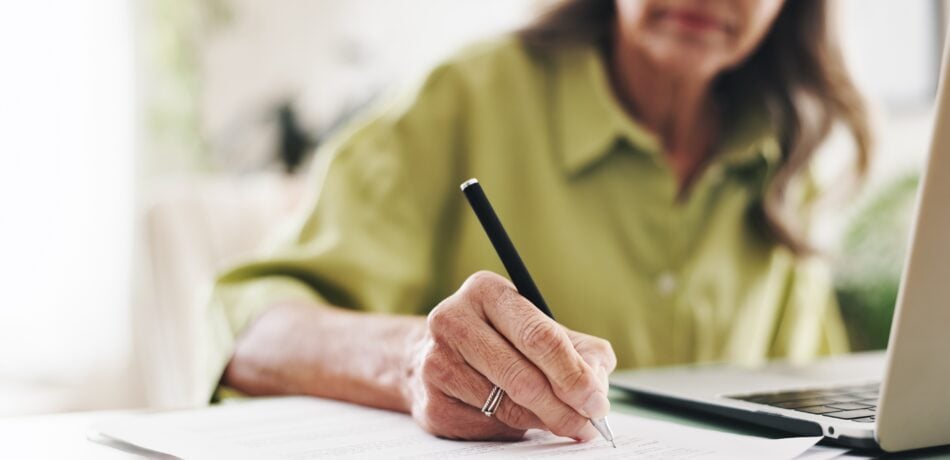 Woman's hand writing in a notebook with a pen.