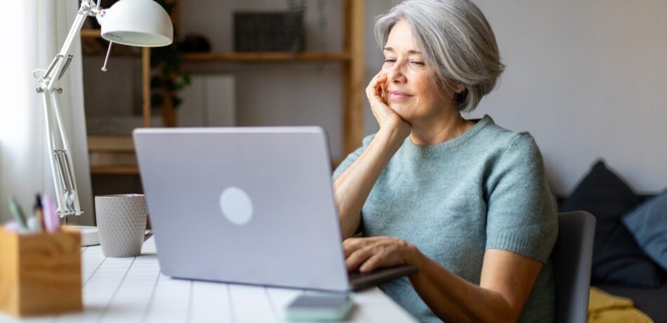 A mature woman researches life insurance options on her laptop at home